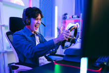 Portrait Of Asian Male Gamer Celebrating Victory In Front Of The Gaming Table. Gamer Winning An Esports Game With Victory Emotion. The Player Rejoices In Victory In The Competition.