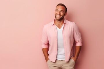 Wall Mural - Portrait of a handsome young man smiling at camera against pink background