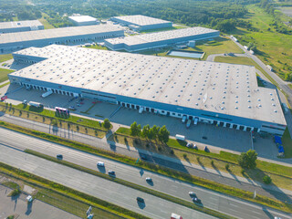 Aerial view of goods warehouse. Logistics center in industrial city zone from above. Aerial view of trucks loading at logistic center