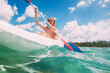 © Soloviova Liudmyla - Underwater view angle to a smiling blonde teenage boy in fashion sunglasses rowing single sit kayak with palm grove background. Active people summer vacation sea concept image, Le Morne, Mauritius.