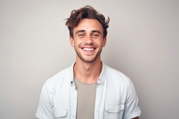 Wall Mural - Portrait of a handsome young man smiling at camera over gray background