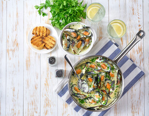 Wall Mural - Tasty seafood in white sauce on a metal pan, top view.