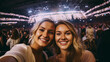 © Keitma - Selfie image of two young women at a concert in a giant indoor arena