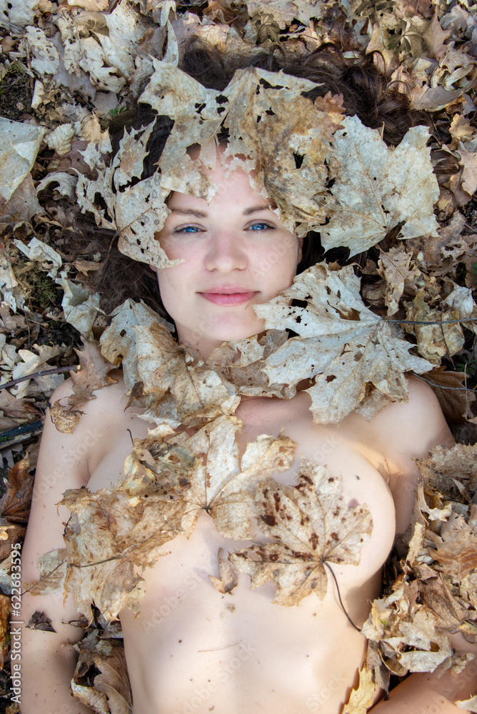 Portrait of beautiful sexy nude young woman with dark brown hair and blue eyes, with white maple