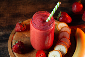 Wall Mural - strawberry smoothie with banana on a wooden table. glass can smoothie with straw