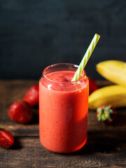 Wall Mural - strawberry smoothie with banana on a wooden table. glass can smoothie with straw