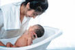 Asian mother take care her newborn baby, bathing in bathtub, adorable newborn infant still sleep, relax and comfortable, newborn baby care concept