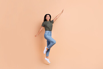 Wall Mural - Full size photo of jumping overjoyed japanese girl have fun wear khaki t-shirt military style brand isolated on beige color background