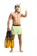 Wall Mural - Full length portrait of a young man in swimwear with a diving mask holding snorkeling fins and gesturing thumbs up