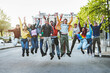 Joyful Multiethnic Youths Jumping in the Street - Group of happy multiethnic young adults aged 18-20 jumping and smiling in the street with raised hands