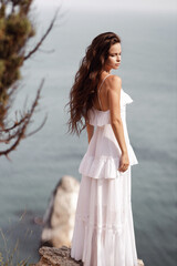 Wall Mural - beautiful woman with dark hair in elegant white dress posing in amazing nature place,