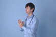 médico clínico fazendo oração com estetoscópio em fundo azul, fé e medicina