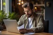 © sirisakboakaew - The depressed young Caucasian man sitting at home office desk on laptop reading documents Millennial men get distracted from computer work. Consider posting paperwork or news correspondents
