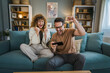 © Miljan Živković - couple man and woman husband wife play smart phone video games at home