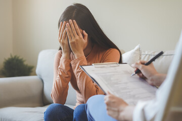 Wall Mural - Psychology, depression. Sad, suffering asian young woman, girl consulting with psychologist, psychiatrist while patient counseling mental with doctor hand taking notes at clinic. Encouraging, therapy.