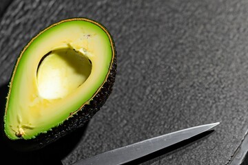 Poster - AI generated illustration of a cut avocado on a cutting board with a knife