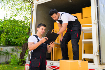 Happy two delivery men in front of delivery truck, Delivery men checking order of moving service and relocation service