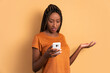 disappointed black woman checking smartphone  in beige colors. communication, app, connection concept.