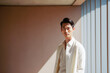 © ADDICTIVE STOCK - Portrait of Asian man with white clothes in minimalist space looking at front. Generative AI.