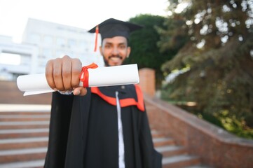 Poster - Portrait of indian handsome male graduate in graduation robe.