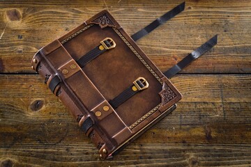 Wall Mural - Aged leather book cover, design with closure belts - captured on wooden table