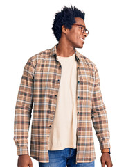 Poster - Handsome african american man with afro hair wearing casual clothes and glasses looking away to side with smile on face, natural expression. laughing confident.