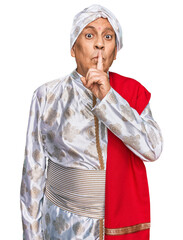 Canvas Print - Senior hispanic man wearing tradition sherwani saree clothes asking to be quiet with finger on lips. silence and secret concept.