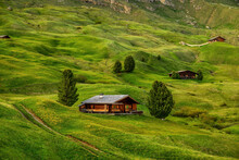 Wooden Huts On The Grassy Hillside Of The Seceda Peak In The Italian Dolomites 