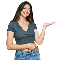 Sticker - Young beautiful teen girl wearing casual crop top t shirt smiling cheerful presenting and pointing with palm of hand looking at the camera.