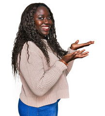 Poster - Young african woman wearing wool winter sweater pointing aside with hands open palms showing copy space, presenting advertisement smiling excited happy