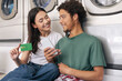 © Prostock-studio - Couple At Laundromat Service Holding Credit Card And Using Phone