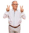 © Krakenimages.com - Senior caucasian man wearing business shirt and glasses smiling looking to the camera showing fingers doing victory sign. number two.