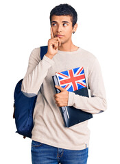 Sticker - Young african amercian man wearing student backpack holding binder and uk flag serious face thinking about question with hand on chin, thoughtful about confusing idea