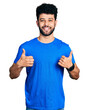 © Krakenimages.com - Young arab man with beard wearing casual blue t shirt success sign doing positive gesture with hand, thumbs up smiling and happy. cheerful expression and winner gesture.