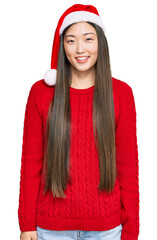 Poster - Young chinese woman wearing christmas hat with a happy and cool smile on face. lucky person.