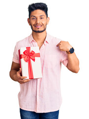 Wall Mural - Handsome latin american young man holding gift pointing finger to one self smiling happy and proud