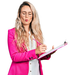 Poster - Young blonde woman writing on clipboard making fish face with mouth and squinting eyes, crazy and comical.