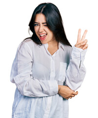 Wall Mural - Beautiful hispanic woman wearing casual white shirt smiling with happy face winking at the camera doing victory sign. number two.