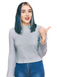 © Krakenimages.com - Young modern girl wearing casual sweater smiling with happy face looking and pointing to the side with thumb up.
