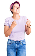 Canvas Print - Young beautiful woman with pink hair wearing casual clothes very happy and excited doing winner gesture with arms raised, smiling and screaming for success. celebration concept.