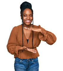 Sticker - Young african american woman wearing casual clothes gesturing with hands showing big and large size sign, measure symbol. smiling looking at the camera. measuring concept.