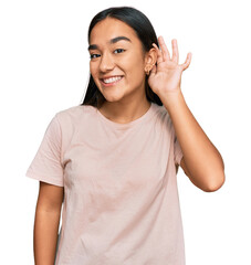 Wall Mural - Young asian woman wearing casual clothes smiling with hand over ear listening an hearing to rumor or gossip. deafness concept.