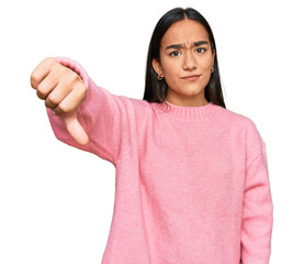 Wall Mural - Young asian woman wearing casual winter sweater looking unhappy and angry showing rejection and negative with thumbs down gesture. bad expression.