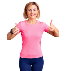 Wall Mural - Young blonde woman wearing sportswear success sign doing positive gesture with hand, thumbs up smiling and happy. cheerful expression and winner gesture.