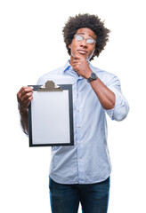 Sticker - Afro american man holding clipboard over isolated background serious face thinking about question, very confused idea