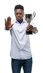 Canvas Print - Young african american man holding trophy with open hand doing stop sign with serious and confident expression, defense gesture