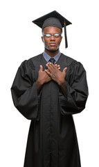 Wall Mural - Young graduated african american man over isolated background smiling with hands on chest with closed eyes and grateful gesture on face. Health concept.