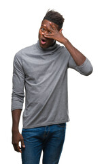 Sticker - Young african american man over isolated background peeking in shock covering face and eyes with hand, looking through fingers with embarrassed expression.