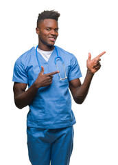 Poster - Young african american doctor man over isolated background wearing surgeon uniform smiling and looking at the camera pointing with two hands and fingers to the side.