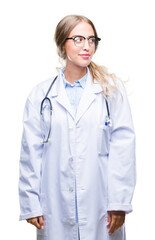 Poster - Beautiful young blonde doctor woman wearing medical uniform over isolated background smiling looking side and staring away thinking.